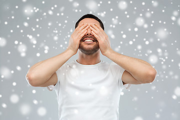 Image showing smiling man closing his eyes over snow background