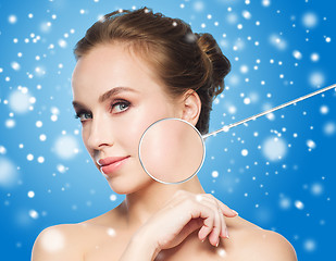 Image showing beautiful woman with magnifier on face over snow