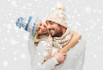 Image showing smiling couple in winter clothes hugging over snow