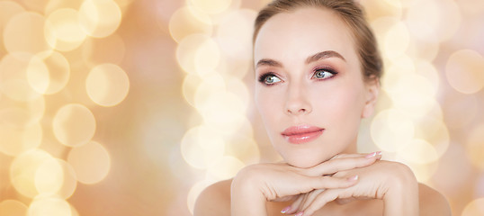 Image showing beautiful young woman face and hands over lights