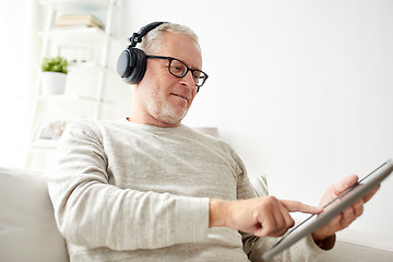 Image showing senior man with tablet pc and headphones at home