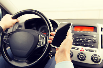 Image showing close up of man hand with smartphone driving car