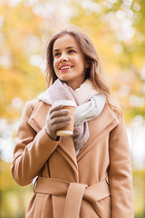 Image showing happy young woman drinking coffee in autumn park