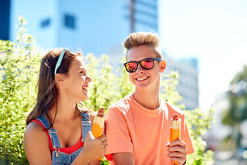 Image showing happy teenage couple eating hot dogs in city