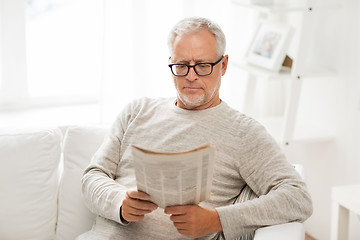 Image showing senior man in glasses reading newspaper at home