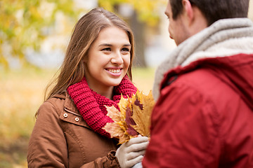 Image showing happy couple with maple leaves in autumn park