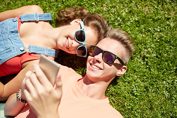 Image showing happy teenage couple smartphone lying on grass