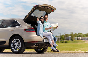 Image showing happy man and woman with road map at hatchback car
