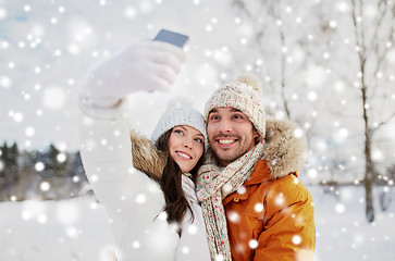 Image showing happy couple taking selfie by smartphone in winter