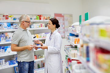 Image showing pharmacist and senior man buying drug at pharmacy