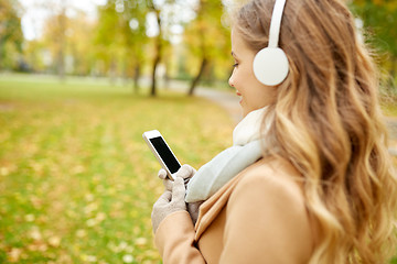 Image showing woman with smartphone and earphones in autumn park