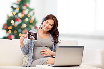 Image showing happy pregnant woman with ultrasound image at home