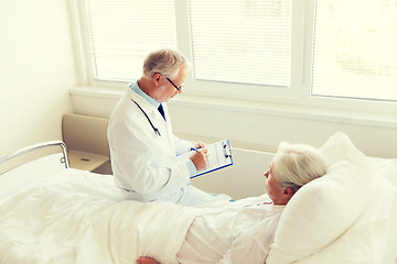 Image showing senior woman and doctor with clipboard at hospital