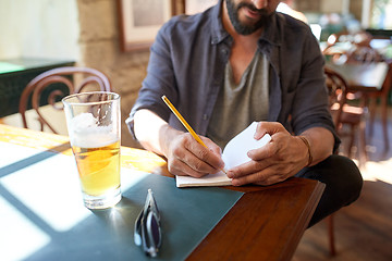 Image showing close up of man with beer and notebook at pub