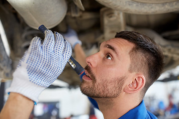 Image showing mechanic man with flashlight repairing car at shop