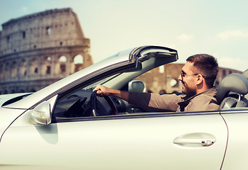 Image showing happy man driving cabriolet car over coliseum