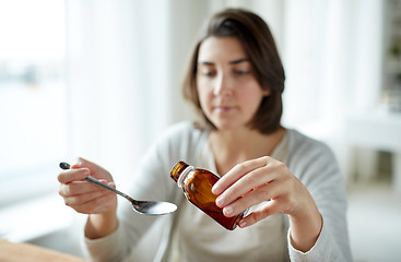 Image showing woman pouring medication from bottle to spoon