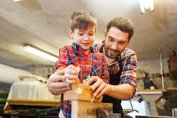 Image showing father and son with plane shaving wood at workshop