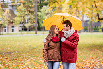 Image showing smiling couple with umbrella in autumn park