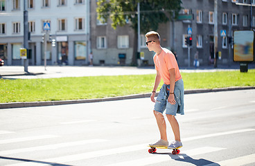 Image showing teenage boy on skateboard crossing city crosswalk