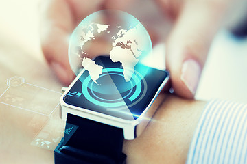 Image showing close up of hand with globe hologram on smartwatch