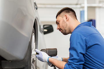 Image showing mechanic with screwdriver changing car tire