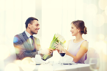 Image showing smiling man giving flower bouquet at restaurant