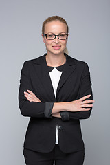 Image showing Business woman standing with arms crossed against gray background..