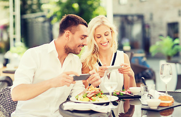 Image showing happy couple with smatphone photographing food