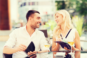 Image showing happy couple with wallet paying bill at restaurant