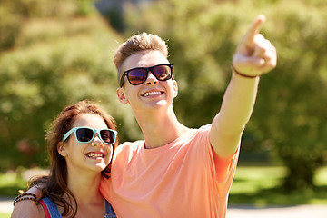 Image showing happy couple pointing finger at summer park