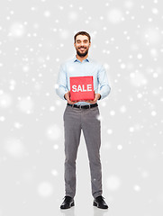 Image showing smiling man with red sale sign over snow