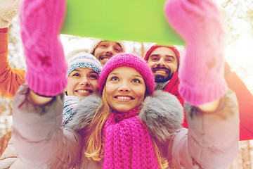 Image showing smiling friends with tablet pc in winter forest