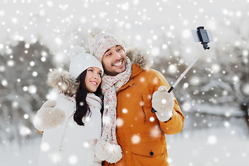 Image showing happy couple taking selfie by smartphone in winter