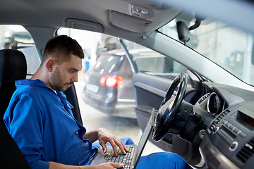 Image showing mechanic man with laptop making car diagnostic