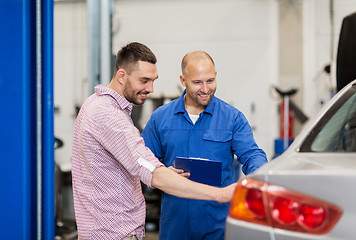 Image showing auto mechanic with clipboard and man at car shop