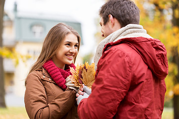 Image showing happy couple with maple leaves in autumn park