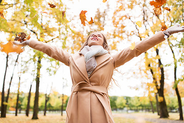 Image showing happy woman having fun with leaves in autumn park