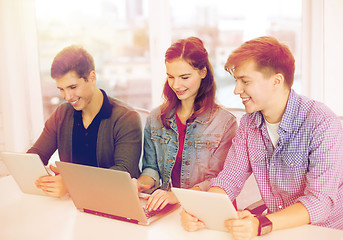 Image showing three smiling students with laptop and tablet pc