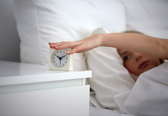 Image showing close up of woman with alarm clock in bed at home