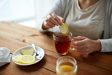 Image showing close up of woman adding lemon to tea cup