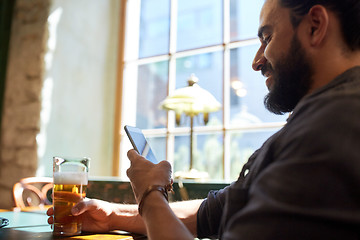 Image showing close up of man with smartphone and beer at pub