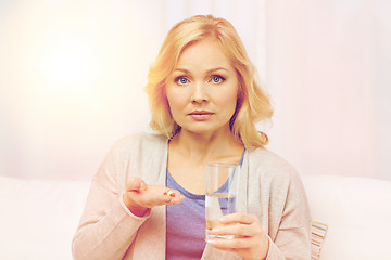 Image showing woman with medicine and water glass at home