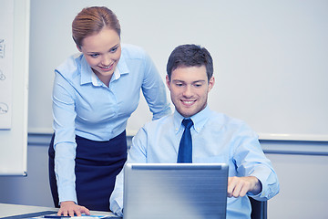 Image showing smiling businesspeople with laptop in office