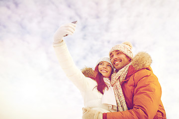 Image showing happy couple taking selfie by smartphone in winter