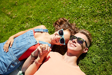 Image showing happy teenage couple lying on grass at summer