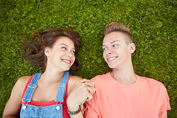 Image showing happy teenage couple lying on grass at summer