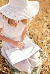 Image showing close up of woman reading book on cereal field