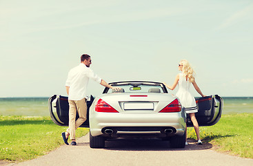 Image showing happy man and woman near cabriolet car at sea