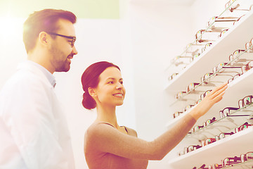 Image showing woman showing glasses to optician at optics store